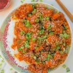 General Tso's Chicken on a plate with rice and chopsticks.