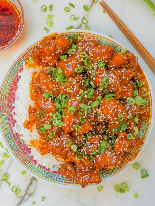 General Tso's Chicken on a plate with rice and chopsticks.