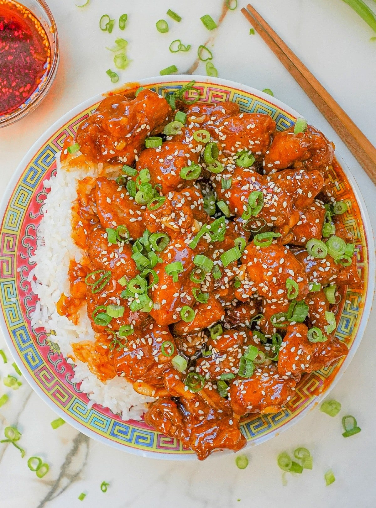 General Tso's Chicken on a plate with rice and chopsticks.