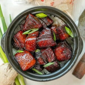 Hong Shao Rou (Chinese Red Braised Pork) in a black pot with rice.