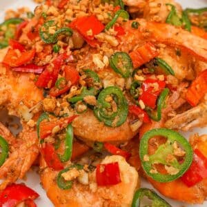Salt and Pepper Shrimp on a plate with jalapenos, red chilis and fried garlic.