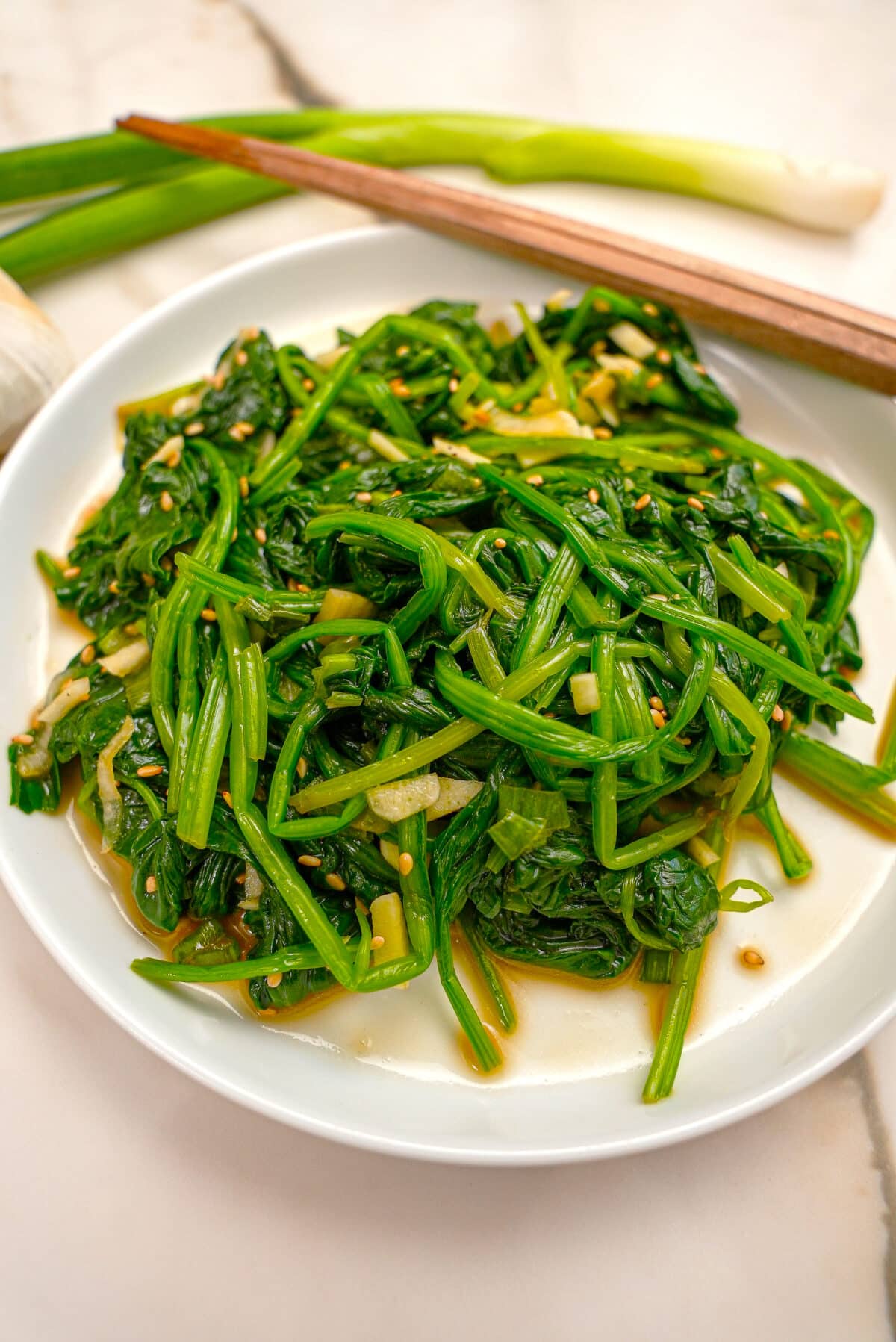 Korean spinach side dish prepared on a plate with chopsticks.