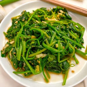 Korean spinach side dish prepared on a plate with chopsticks.