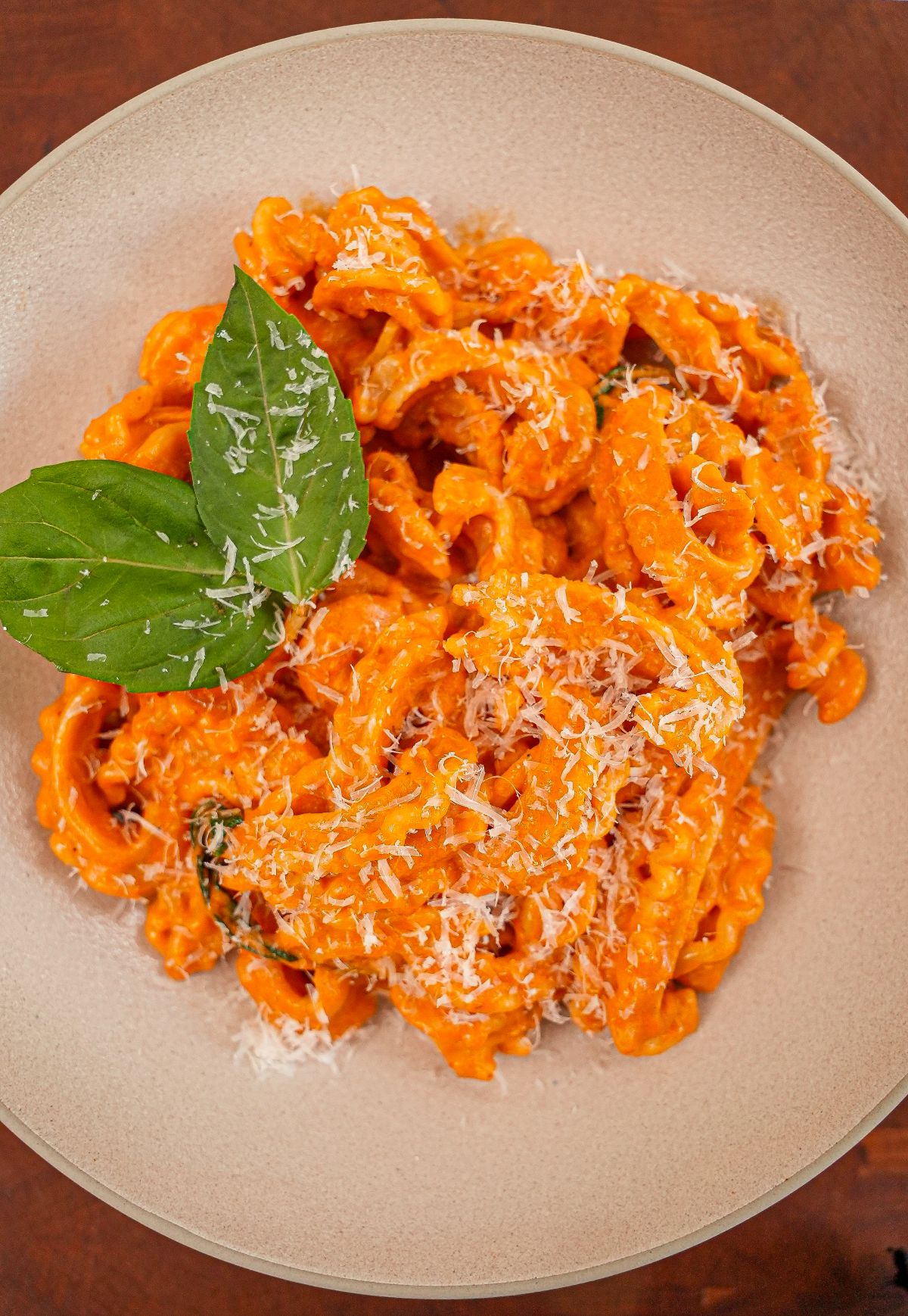 Spicy Vodka pasta in a bowl with basil and parmesan cheese.