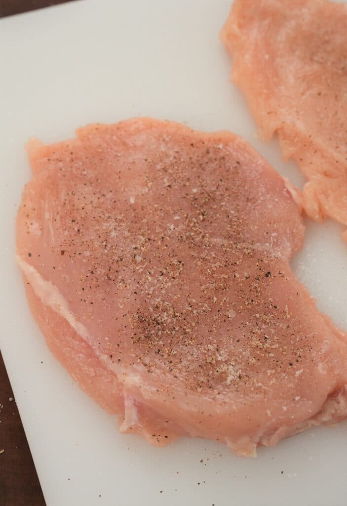 Seasoning chicken fillets with salt and pepper