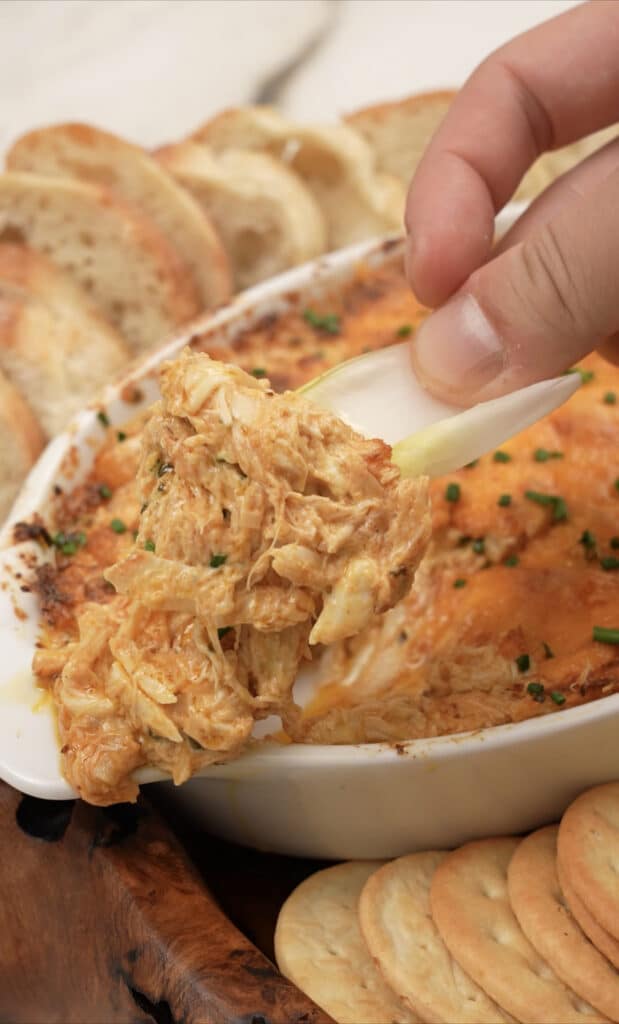 scooping baked crab dip in the pan