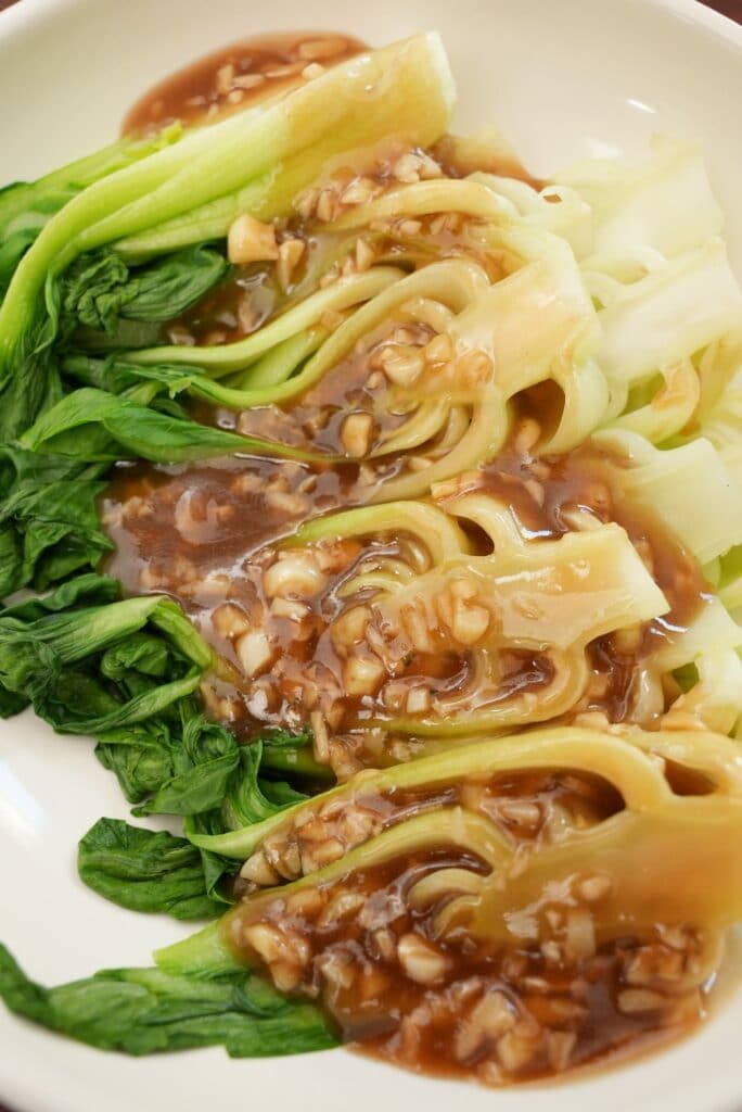 Close up of bok choy with garlic sauce on a plate.