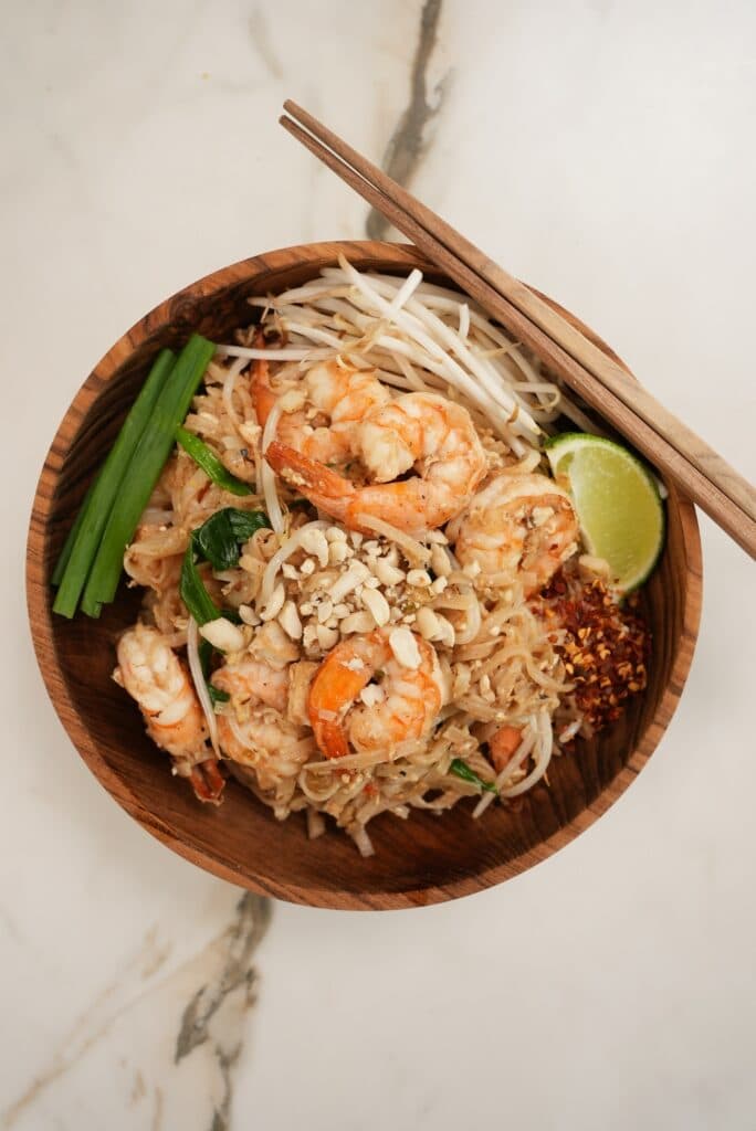 Pad Thai plated in a wooden bowl.