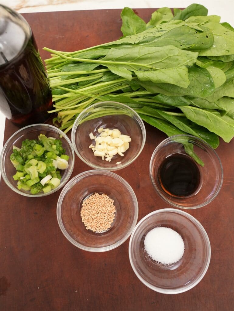 Raw ingredients for Korean Spinach Side Dish on a cutting board.