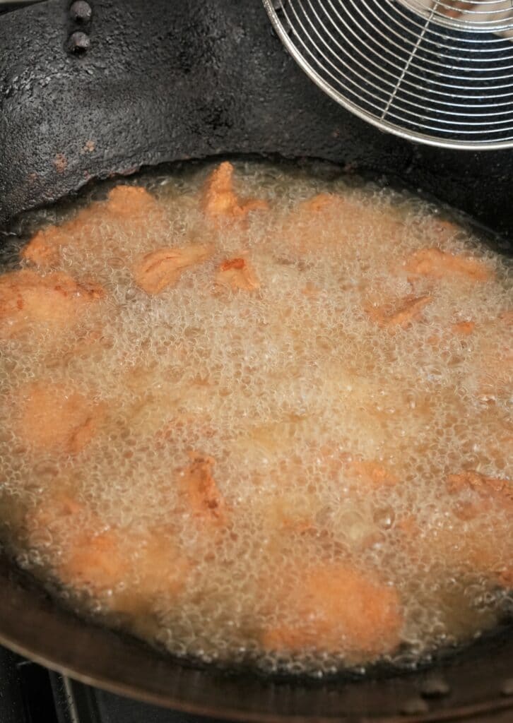 Sesame chicken frying in a wok