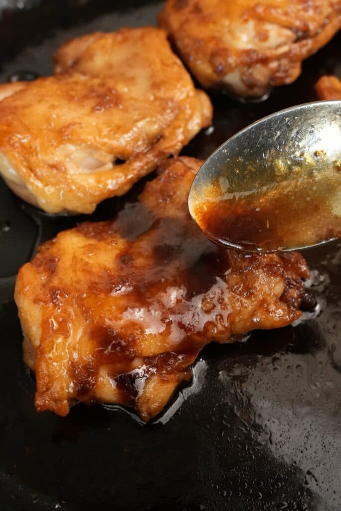 Spooning teriyaki sauce over chicken teriyaki.