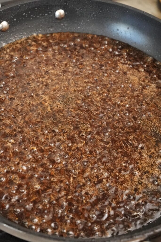 Reducing teriyaki sauce in a pan.