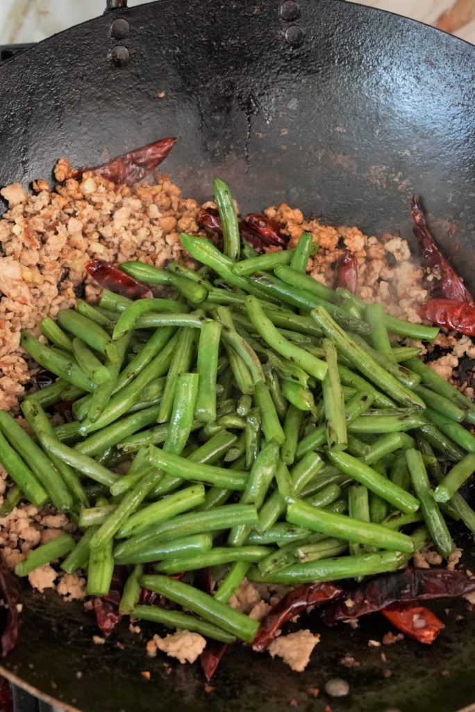green beans with pork and chilis cooking in a pan