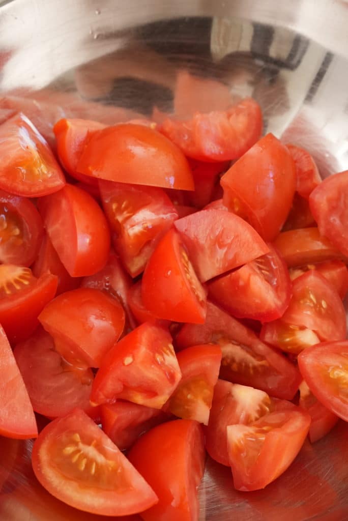 Fresh tomatoes in a metal bowl.