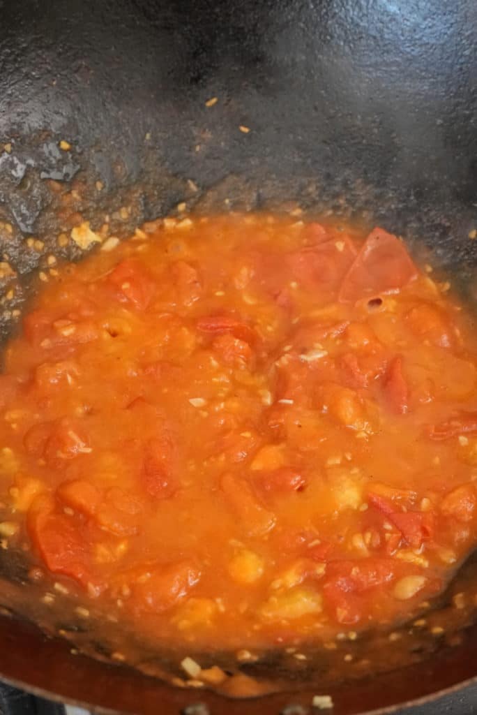 Cooking tomatos, garlic and ginger in a wok.