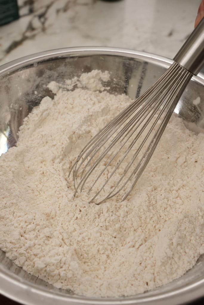 A whisk mixing the fry mix for Korean Fried Chicken.