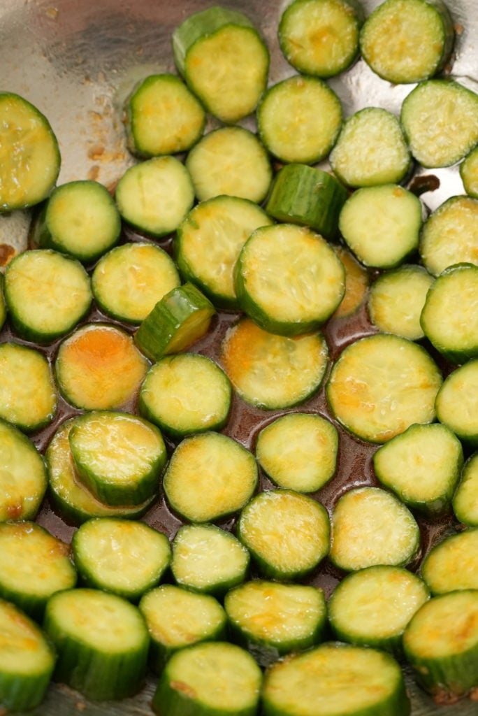 Sliced cucumbers in a bowl with salad dressing