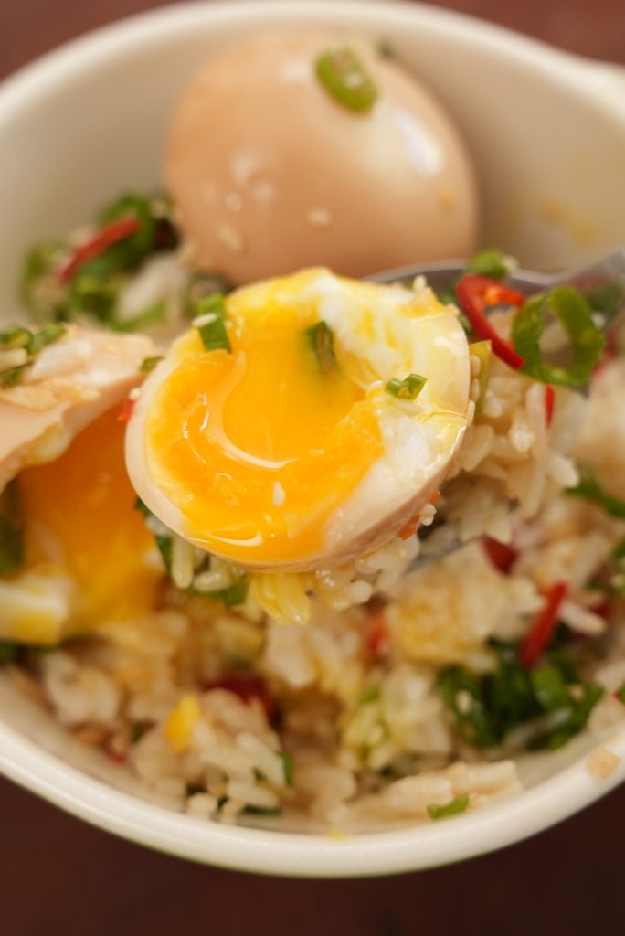 A Korean marinated egg cut in half over a bowl of rice.