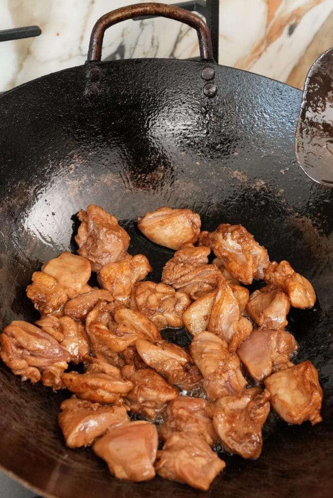 Marinated chicken pieces frying in a wok.
