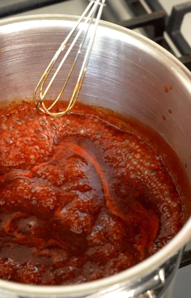 Gochujang glaze simmering and reducing in a sauce pot.