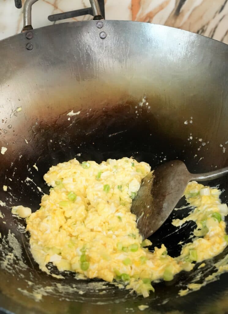 eggs and scallions cooking in a wok