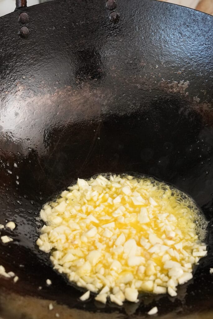 Garlic cooking in butter in a wok.
