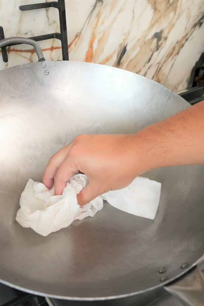 Wiping a wok dry with a paper towel