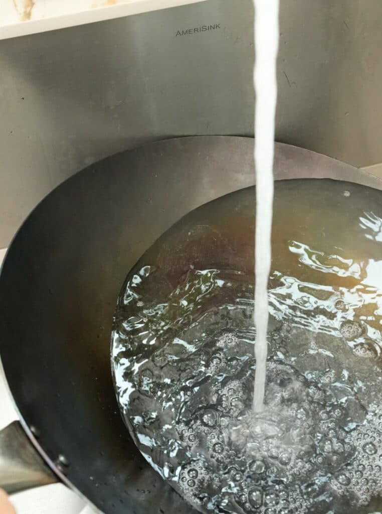 rinsing a seasoned wok with water