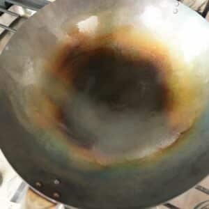 A newly seasoned carbon steel wok on a stove.