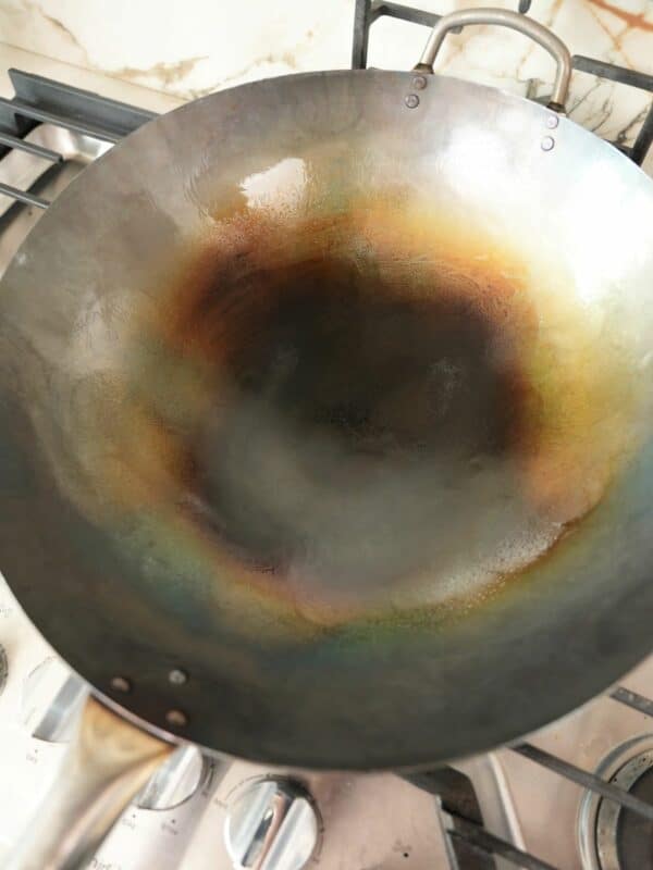 A newly seasoned carbon steel wok on a stove.
