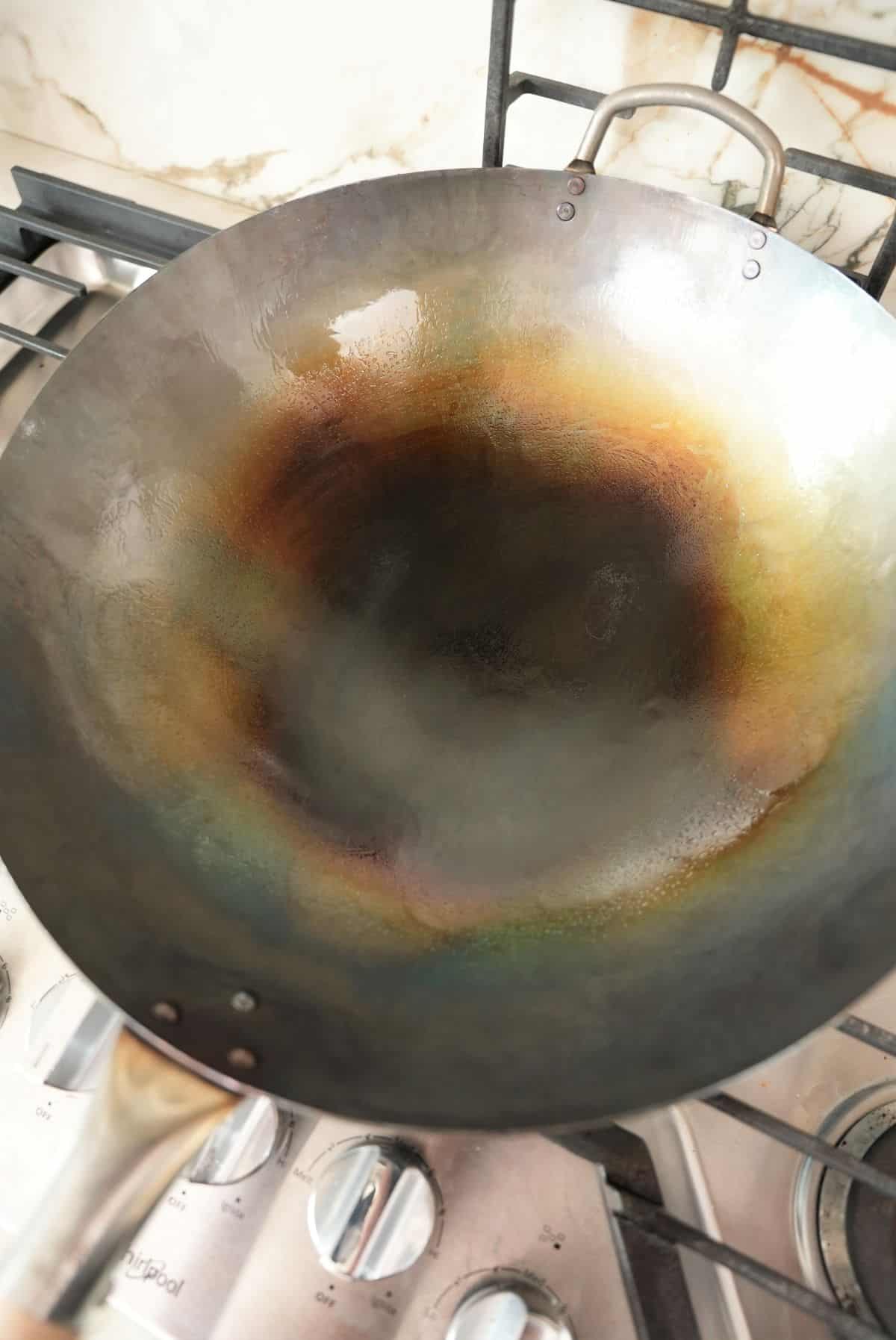 A newly seasoned carbon steel wok on a stove.