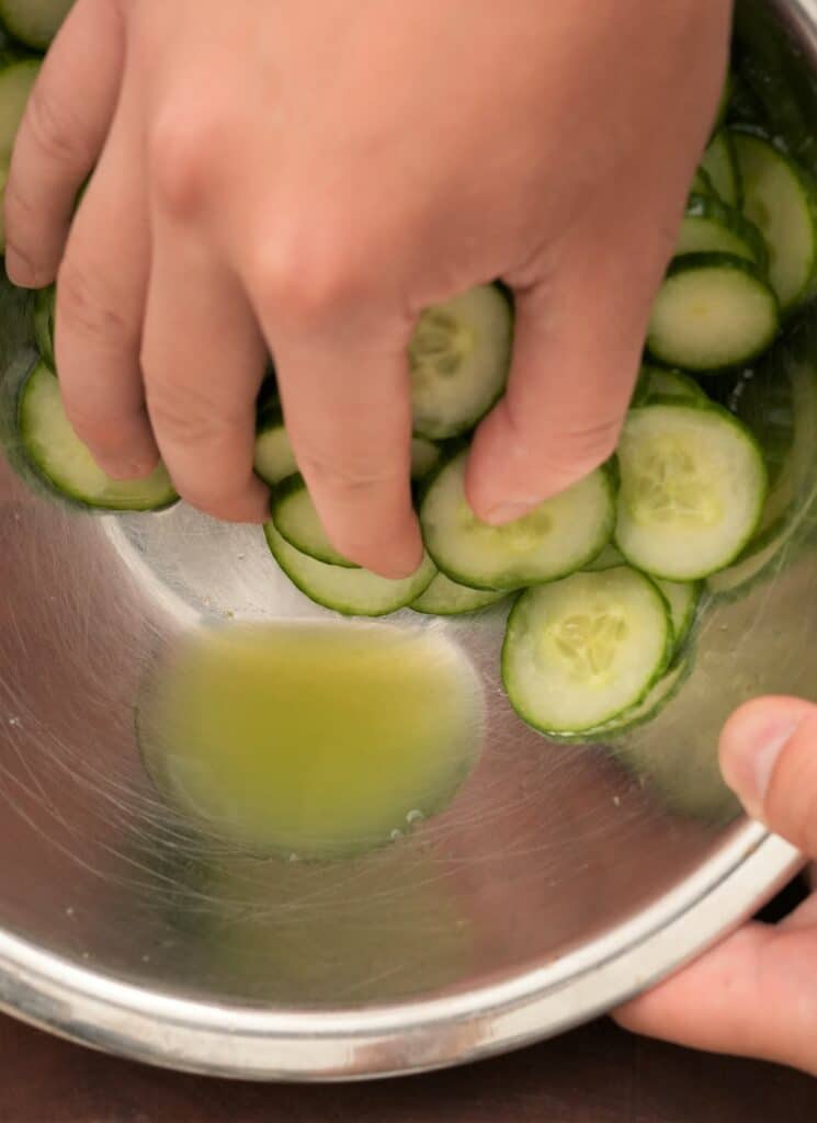 Thinly sliced cucumbers in a bowl with water drained