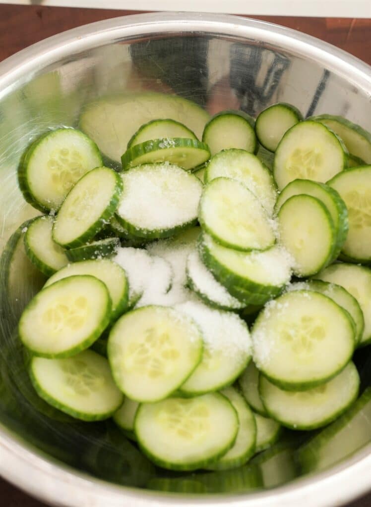 Thinly Sliced Cucumbers in a bowl with salt
