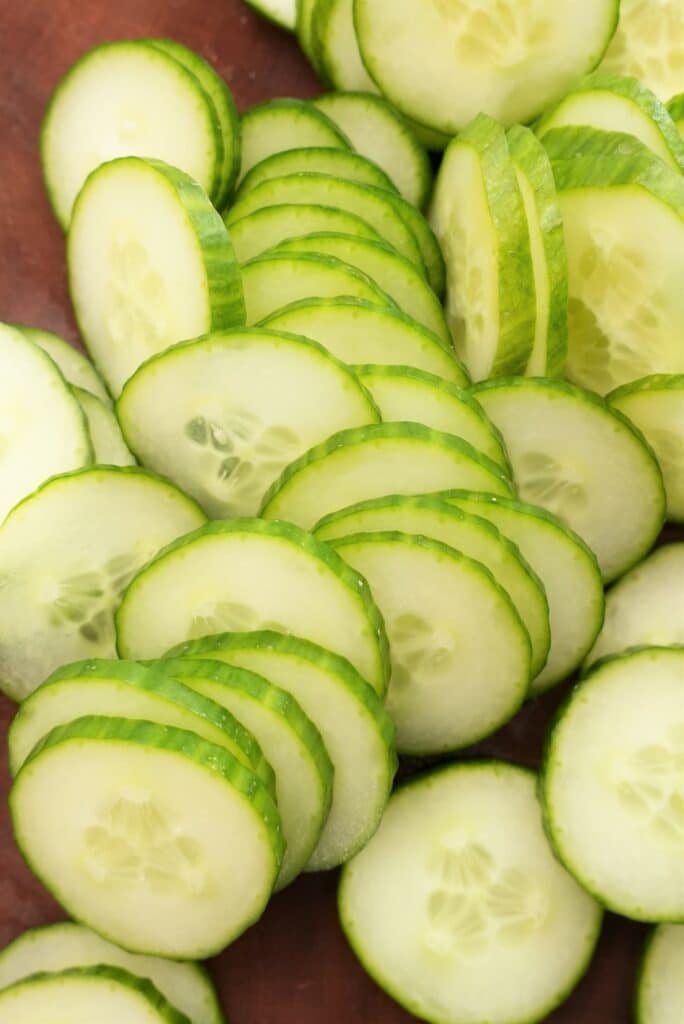 Thinly Sliced Cucumbers on a cutting board.