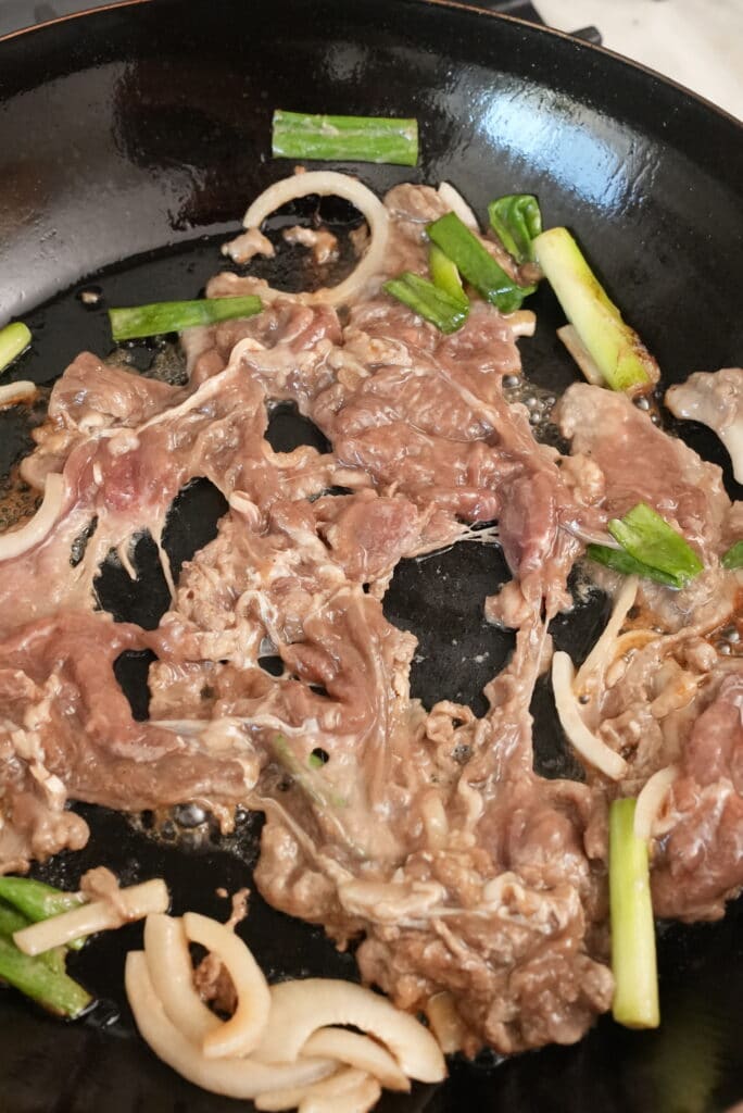 Beef bulgogi cooking in a carbon steel pan