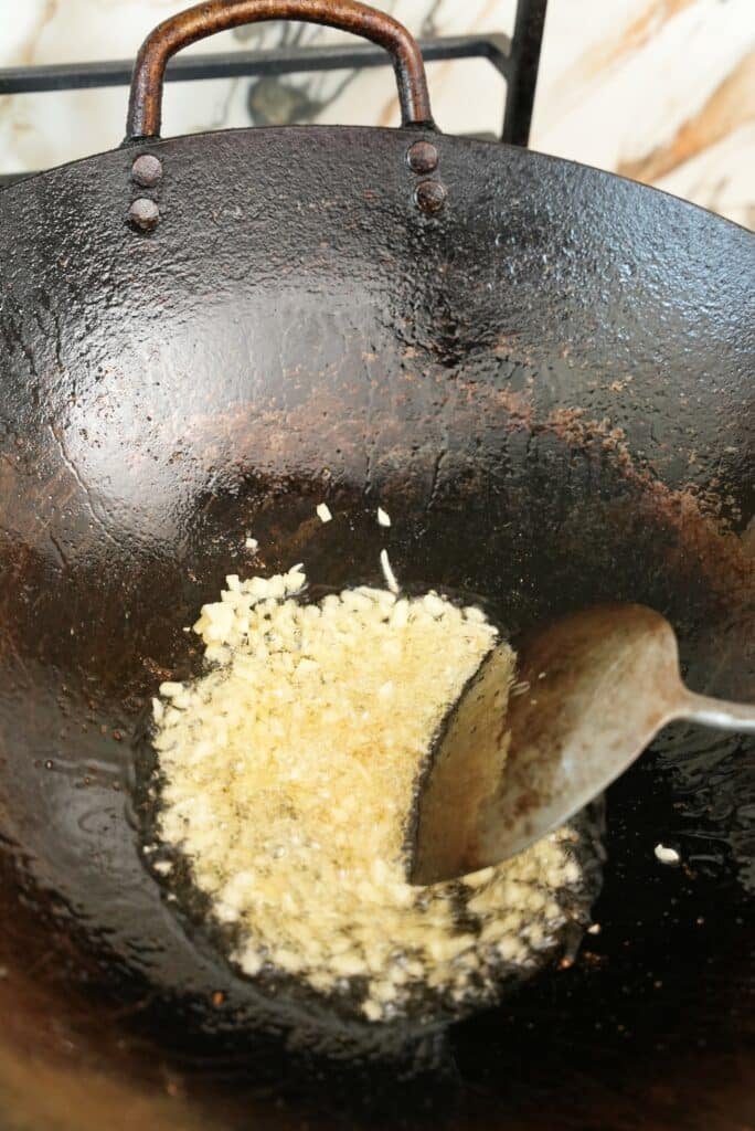 Garlic and ginger frying in oil in a wok.