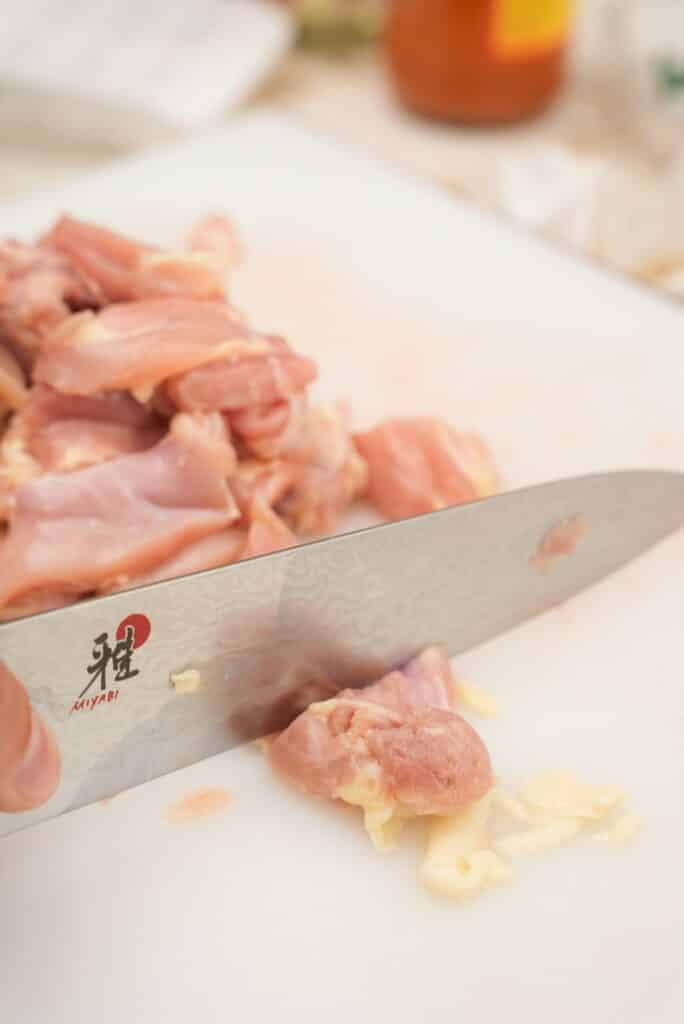 Cutting chicken on a cutting board.