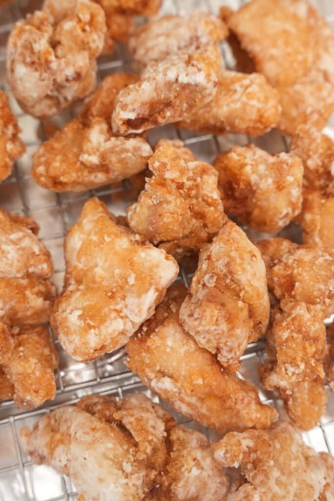 Japanese fried chicken resting on a wire rack after being fried.