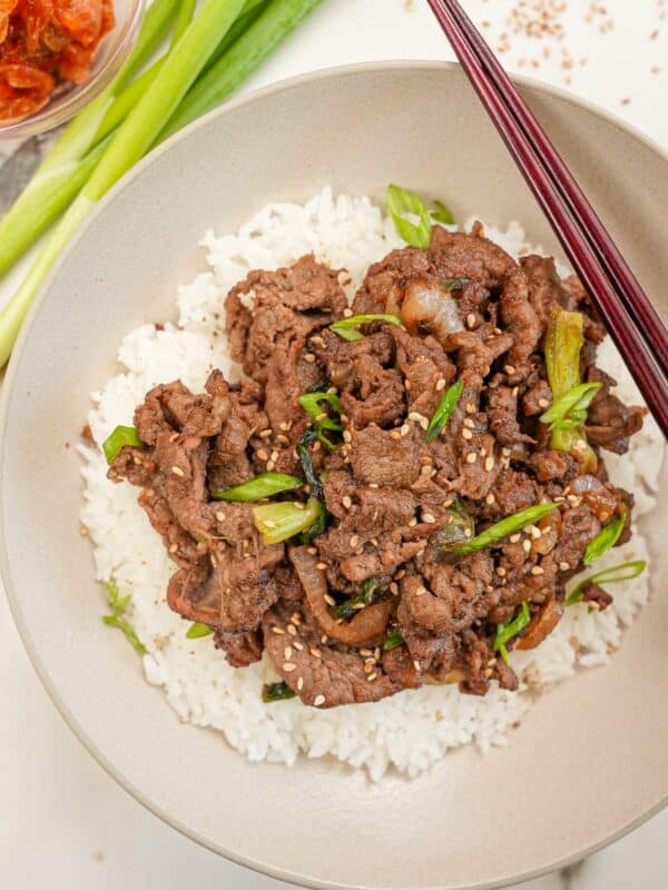 Korean Beef Bulgogi on a plate of rice with kimchi.