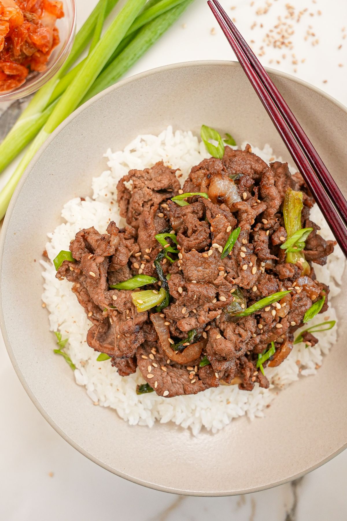 Korean Beef Bulgogi on a plate of rice with kimchi.