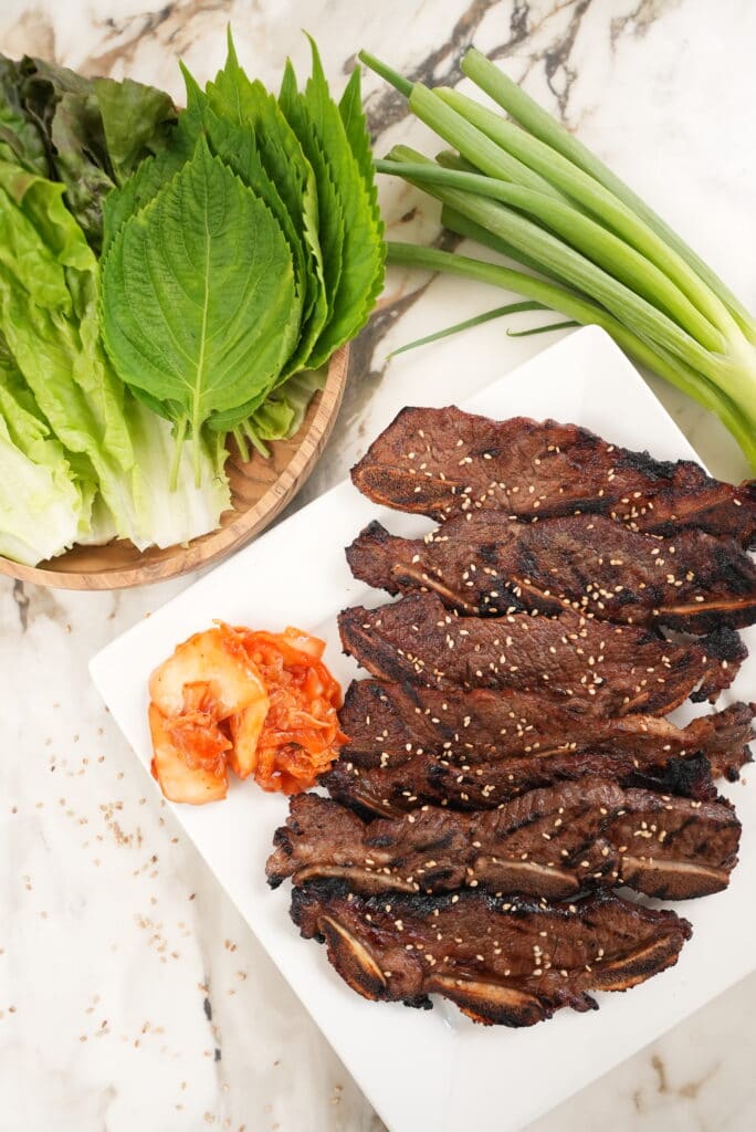 Plated beef short ribs with kimchi and lettuce leaves