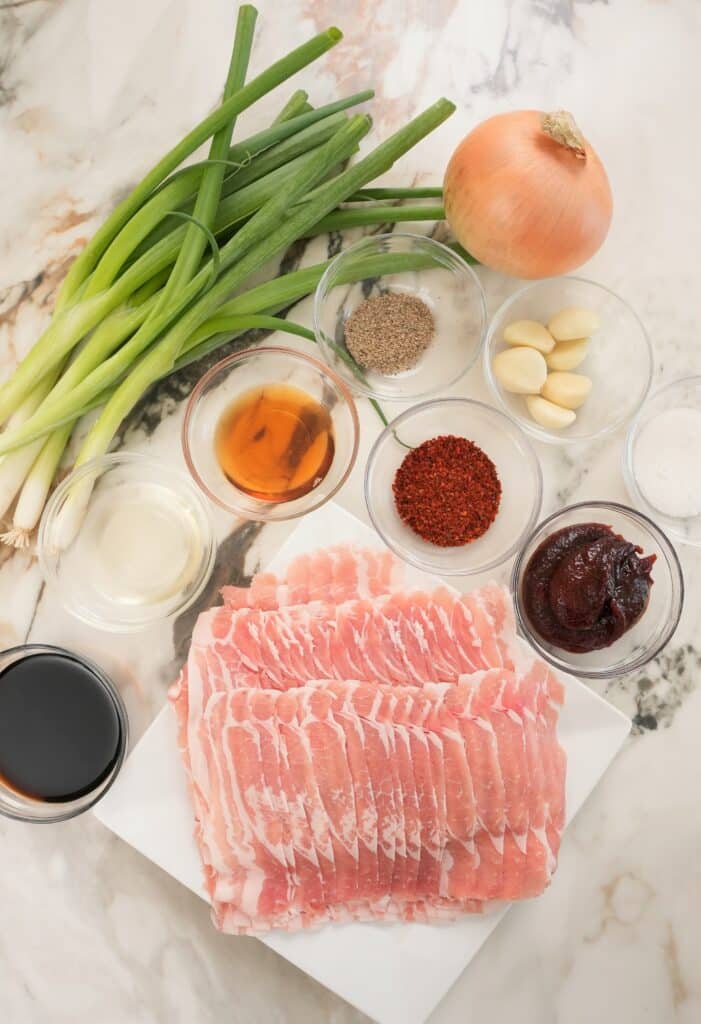 Raw Pork belly and ingredients laid out on a table for Spicy Pork Bulgogi.