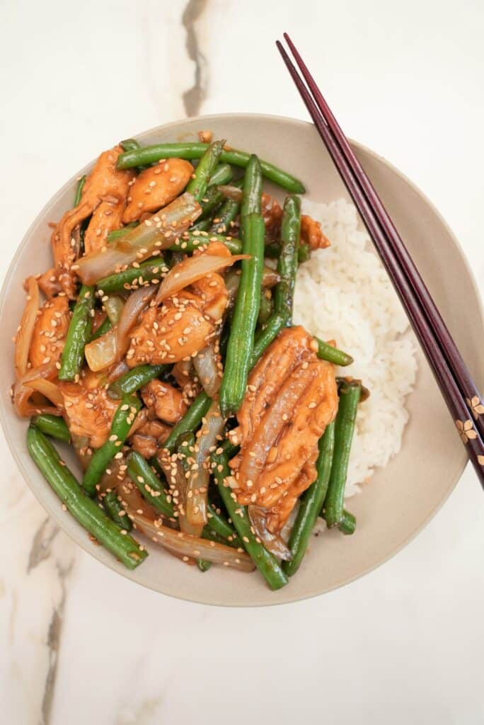 String Bean chicken plated in a bowl with white rice