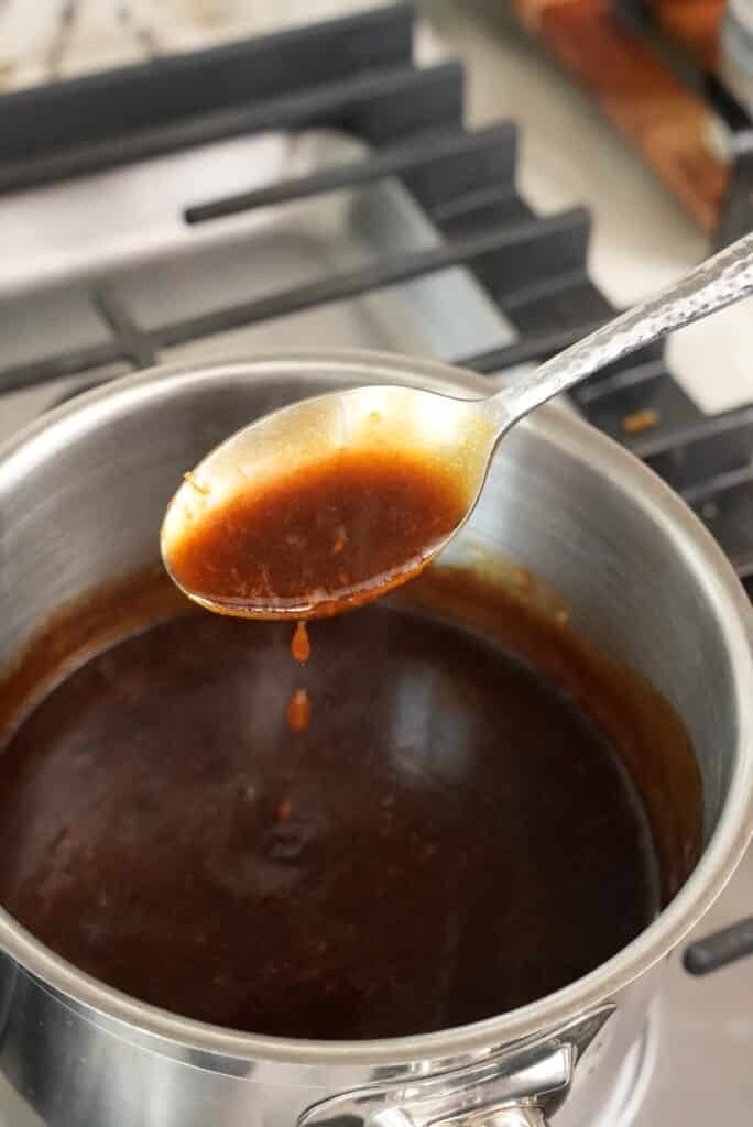 Spoon with oyster sauce over a pot.