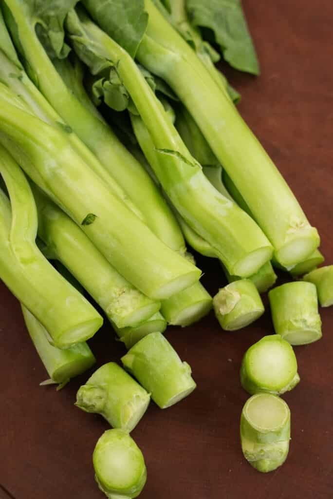 Trimmed stems of gai lan on a cutting board.