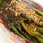A plate of Gai Lan with Oyster Sauce topped with fried garlic on a plate.