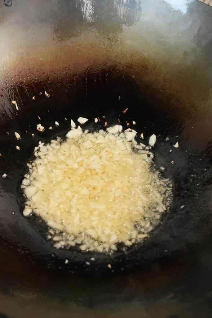 garlic frying in oil in a wok