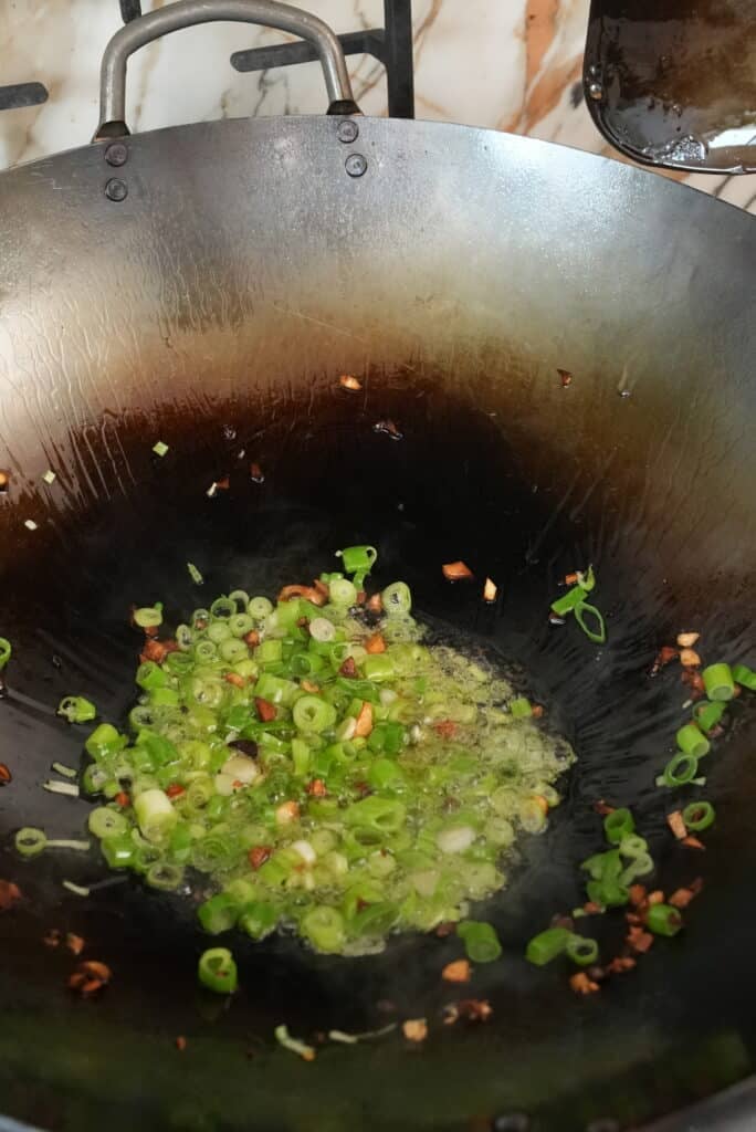 Scallions frying in a wok.