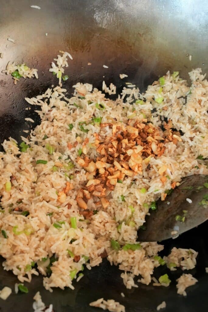 Fried garlic on top of fried rice in a wok.