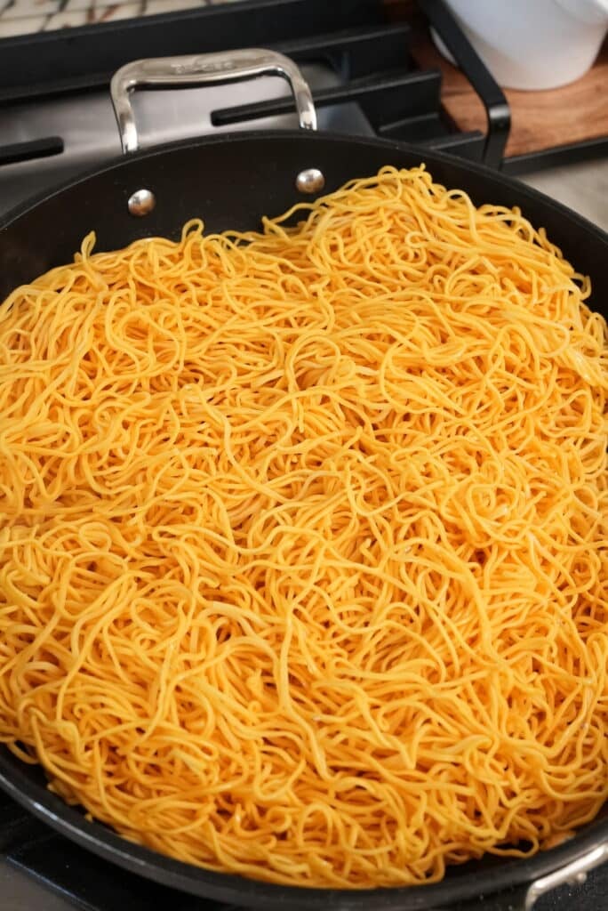 Chow mein noodles pan frying in a pan